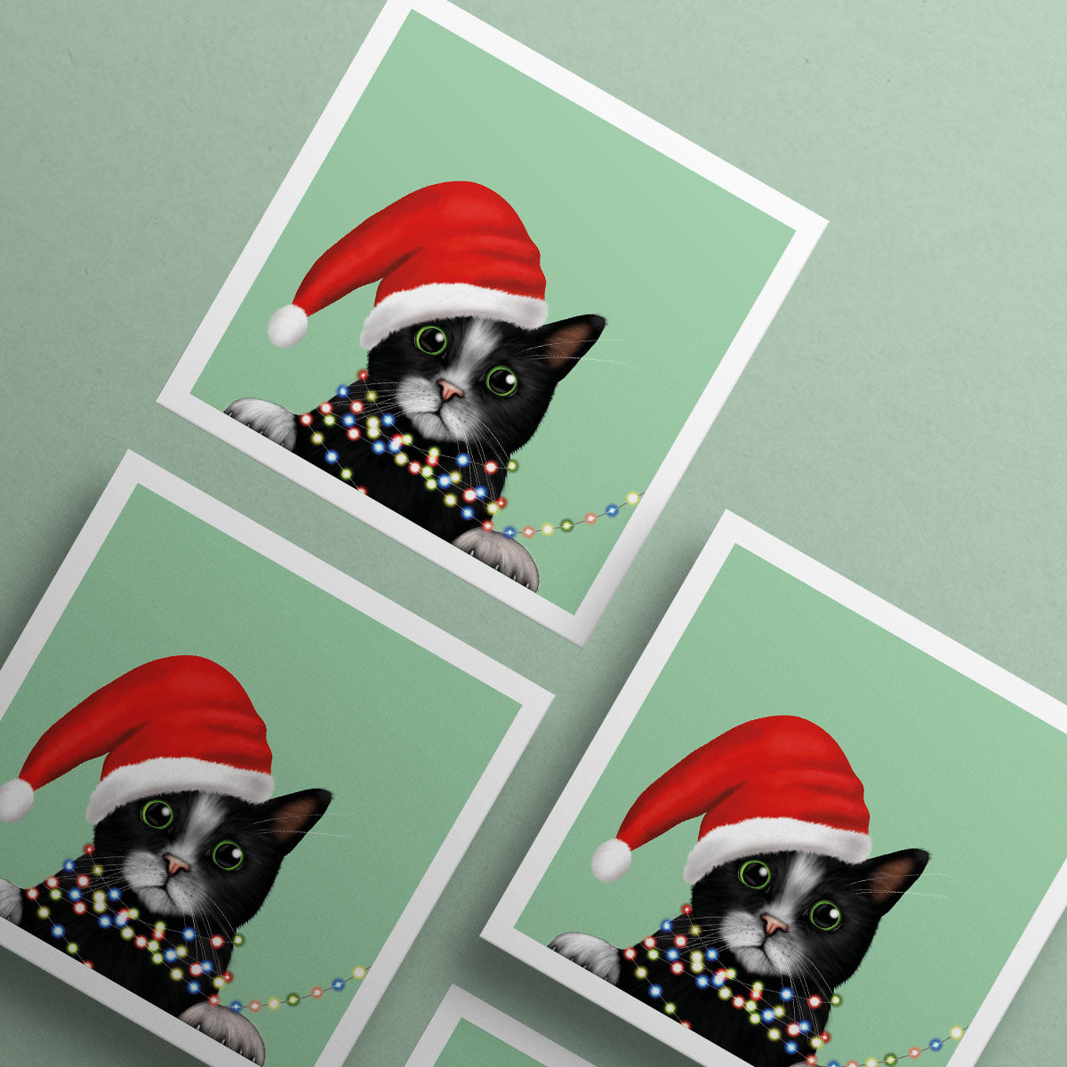 Black and White Cat in Santa Hat wrapped in lights Christmas card by Oundle Artist Kitty's Art
