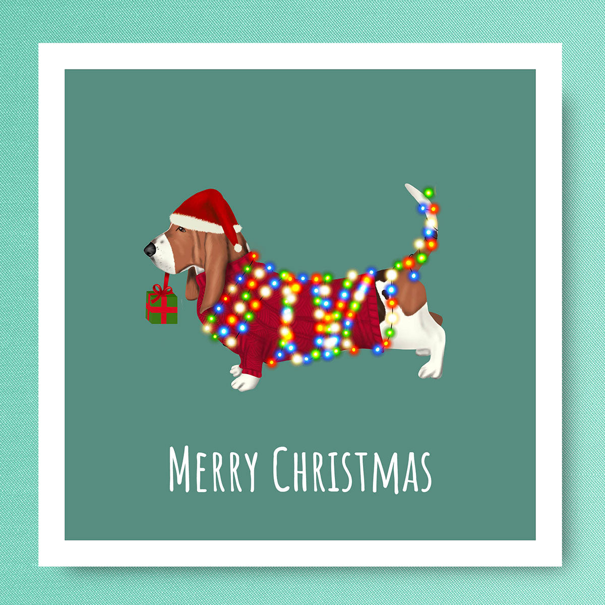 Basset Hound with Red Jumper and Santa Hat wrapped in Lights by Oundle Artist Kitty's Art