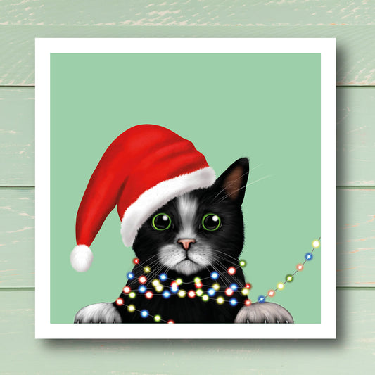 Black and White Cat in Santa Hat wrapped in lights Christmas card by Oundle Artist Kitty's Art